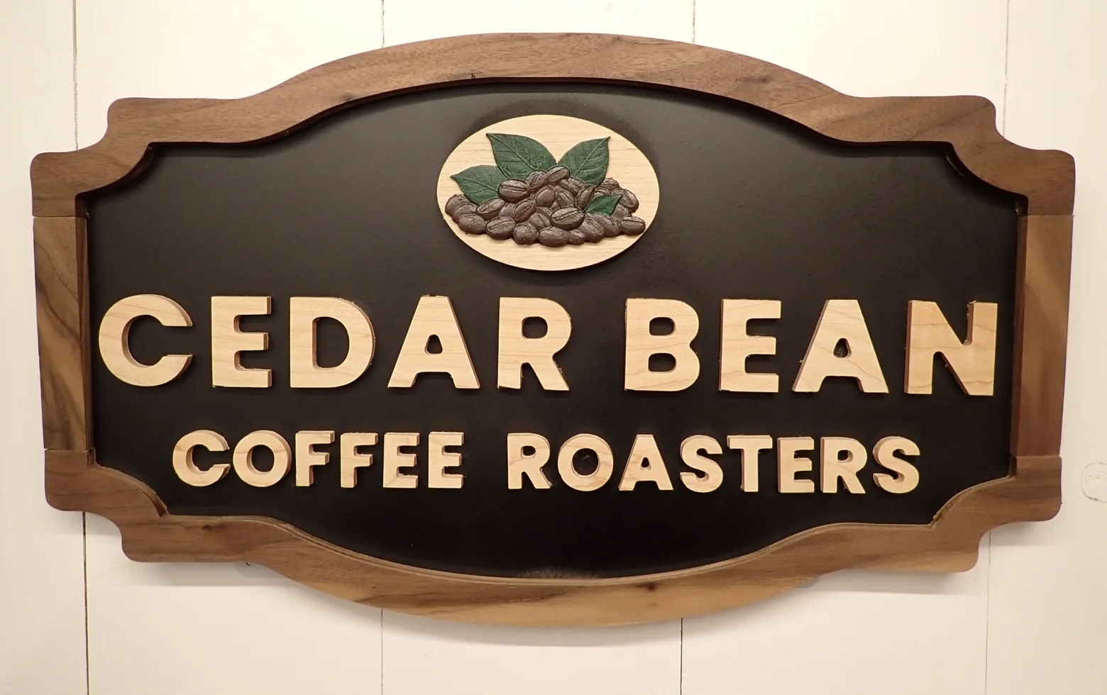 Cedar Bean Coffee Roasters business sign with raised wood lettering, a shaped wood border, and a coffee-bean emblem